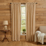 Simmons Plaid red, beige and tan checkered curtain panels hanging on a dark rod in a rustic room with wood-paneled walls, a side table with a lamp, and a chair with a throw blanket.