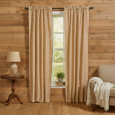 Simmons Plaid red, beige and tan checkered curtain panels hanging on a dark rod in a rustic room with wood-paneled walls, a side table with a lamp, and a chair with a throw blanket.