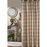 Toffee & Elm Plaid Shower Curtain A beige green and brown plaid shower curtain hanging in a rustic bathroom setting with a white console table, round woven mirror, and potted plants.