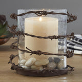 Close-up of Barbed Wire Rustic Pillar Candle Holder and a lit candle on a wooden surface.