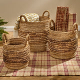 Brinkley Rattan Round Baskets Set of 3 — lifestyle view with throw blanket and woven rug, all three sizes on hardwood floor