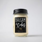 A glass mason jar candle with a black metal lid and a black label reading 'BALSAM & Cedar' on a light gray background.