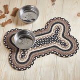 Farmstead Charcoal Dog Bone Braided Waterproof Rug Mat on pine wood floor with stainless dog bowls, dog bone treats, and asphalt bleached white grey taupe braided detail