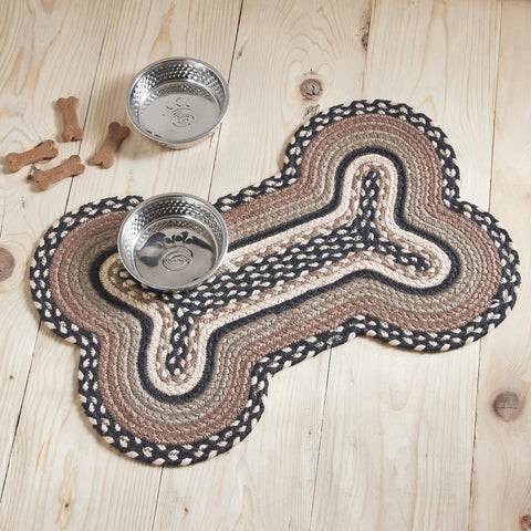 Farmstead Charcoal Dog Bone Braided Waterproof Rug Mat styled on light wood floor with two stainless steel dog bowls and scattered dog treats