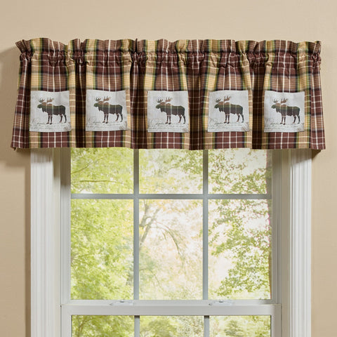 Friar Brown Plaid Moose Patch Valance with moose designs above a window with a view of trees.