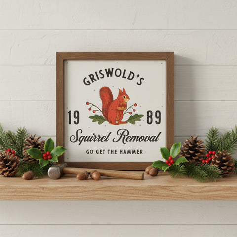 Griswold's Squirrel Removal Holiday Sign 6x6 with a distressed brown wood frame on a wood shelf with Christmas holly and pinecones. The sign features a vintage-style illustration of a red squirrel holding a nut with green leaves and red berries, set against an off-white background.