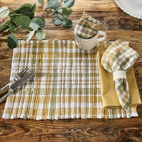 Sage & Mustard Plaid Chindi Placemats Set of 4 with a mug, napkin, and cutlery on a wooden table with eucalyptus leaves.