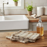 Two Tinderbox Brown Plaid Dishcloths layered on a rustic wood surface with a wooden spoon and fresh basil — waffle weave 100% cotton dishcloths in tinderbox brown, oatmeal and espresso plaid